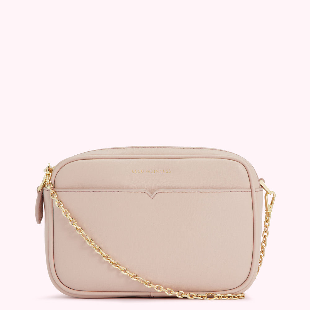 A pale pink leather crossbody bag with a gold chain strap and the brand name "Lulu Guinness" embossed on the front.
