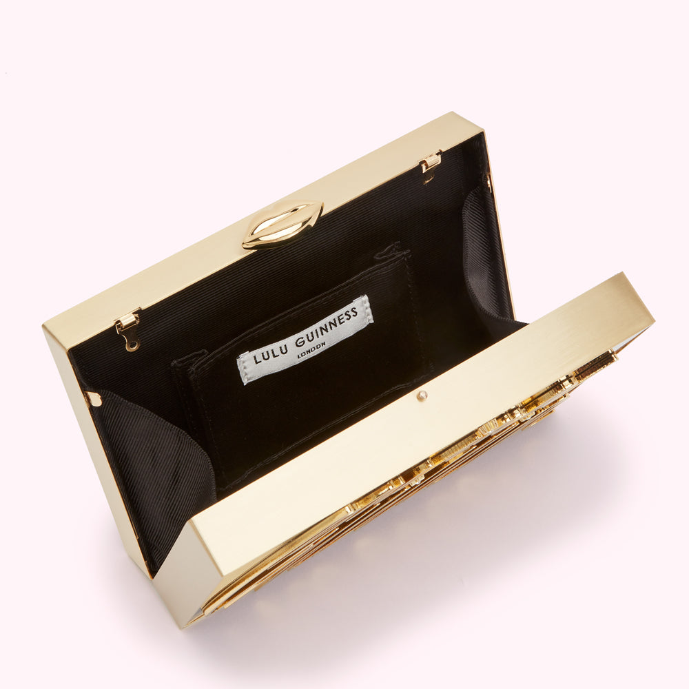 Gold Lulu Guinness clutch open to reveal black satin interior and a small pocket.