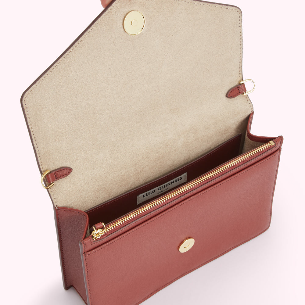 Open red leather Lulu Guinness crossbody bag with beige interior and gold zipper.

