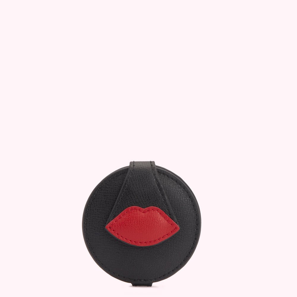 Black round compact mirror with a red lip design.
