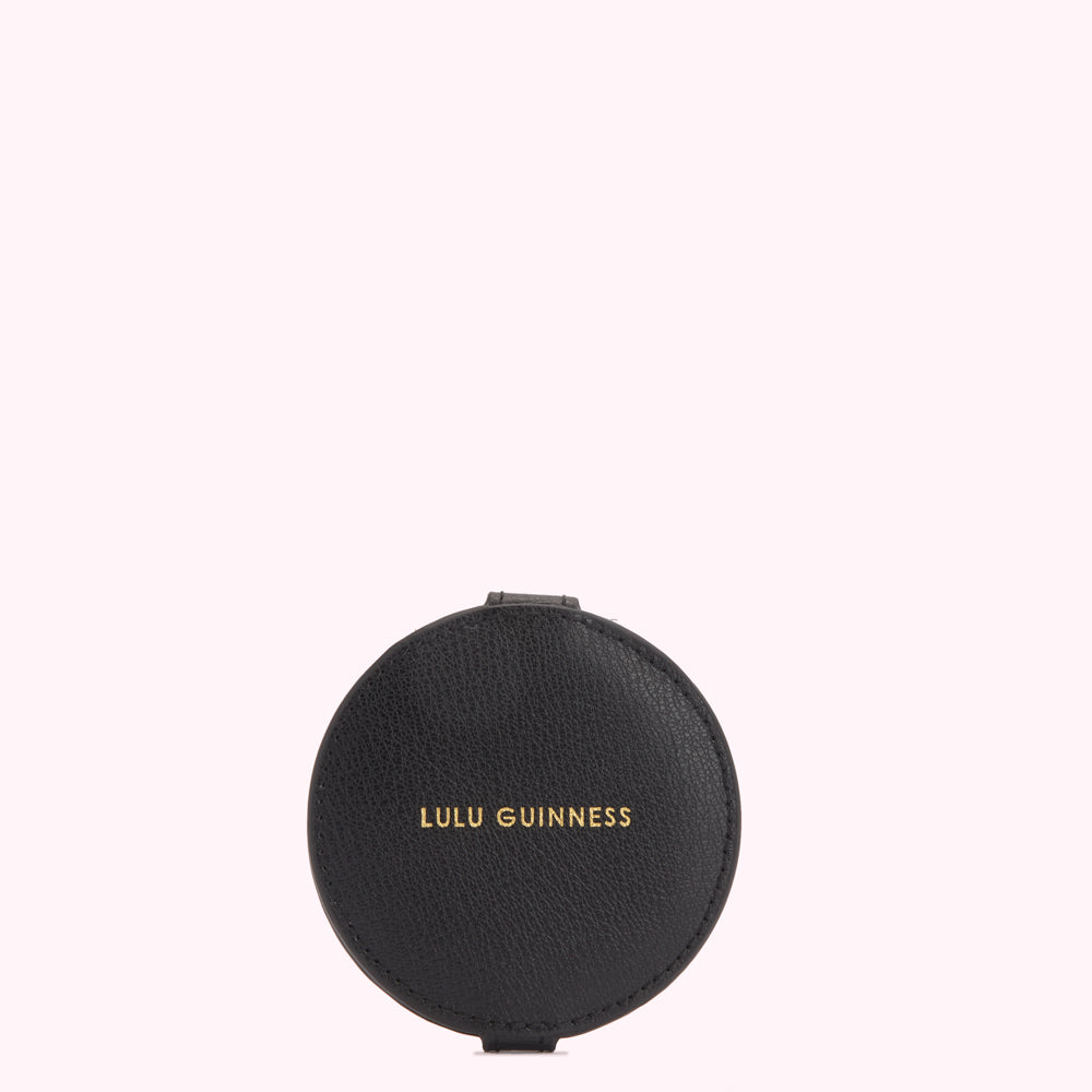 Black round compact mirror with gold Lulu Guinness logo on a white background.
