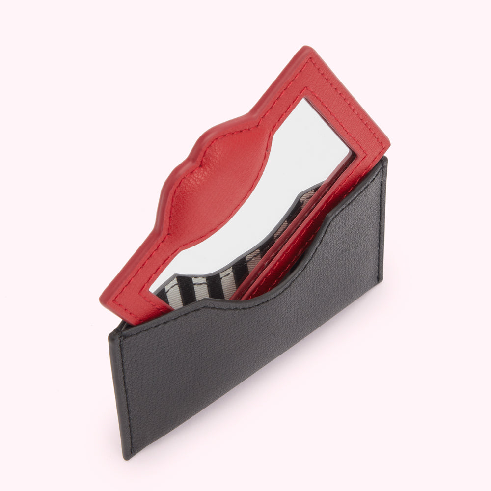 A red lip-shaped compact mirror in a black leather case.