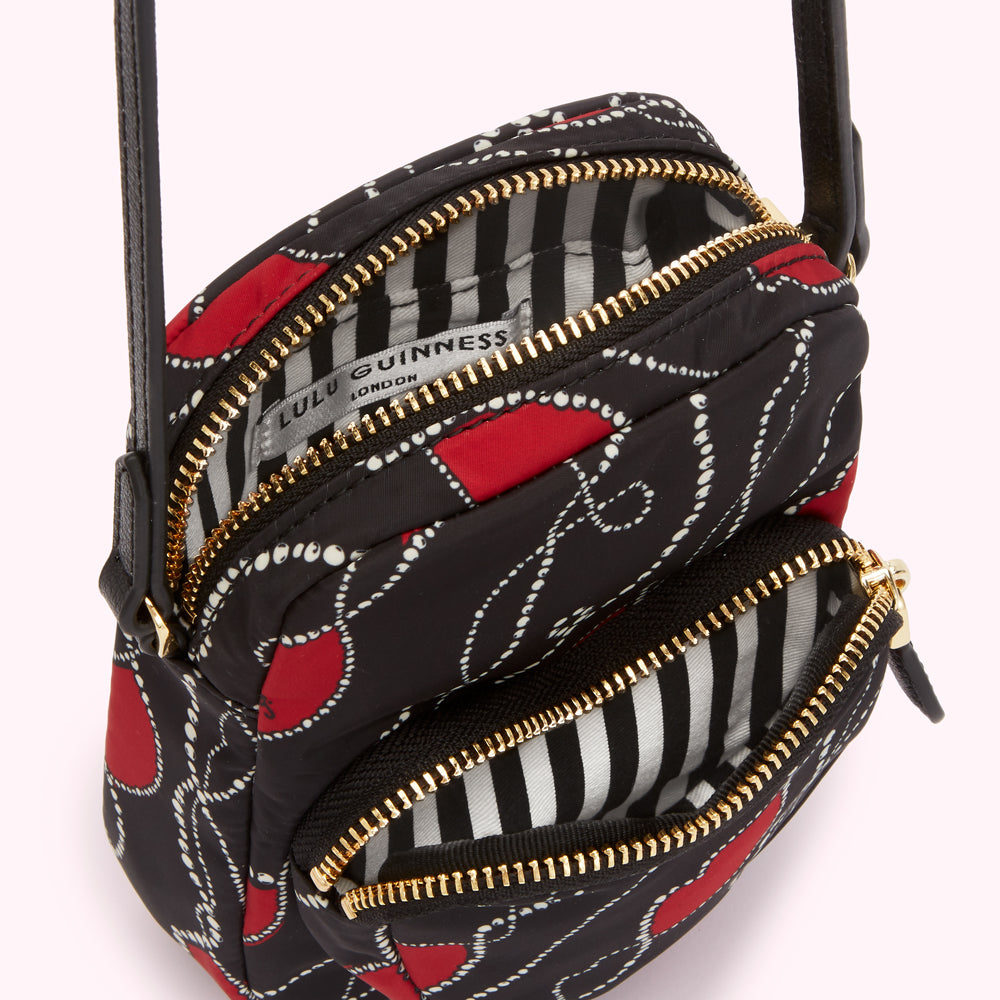 Open Lulu Guinness crossbody bag with black and red pattern and gold zippers.