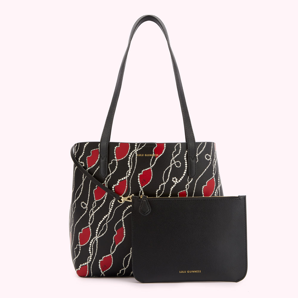 Black Lulu Guinness tote bag with red lips and pearl details, shown with a matching black pouch.
