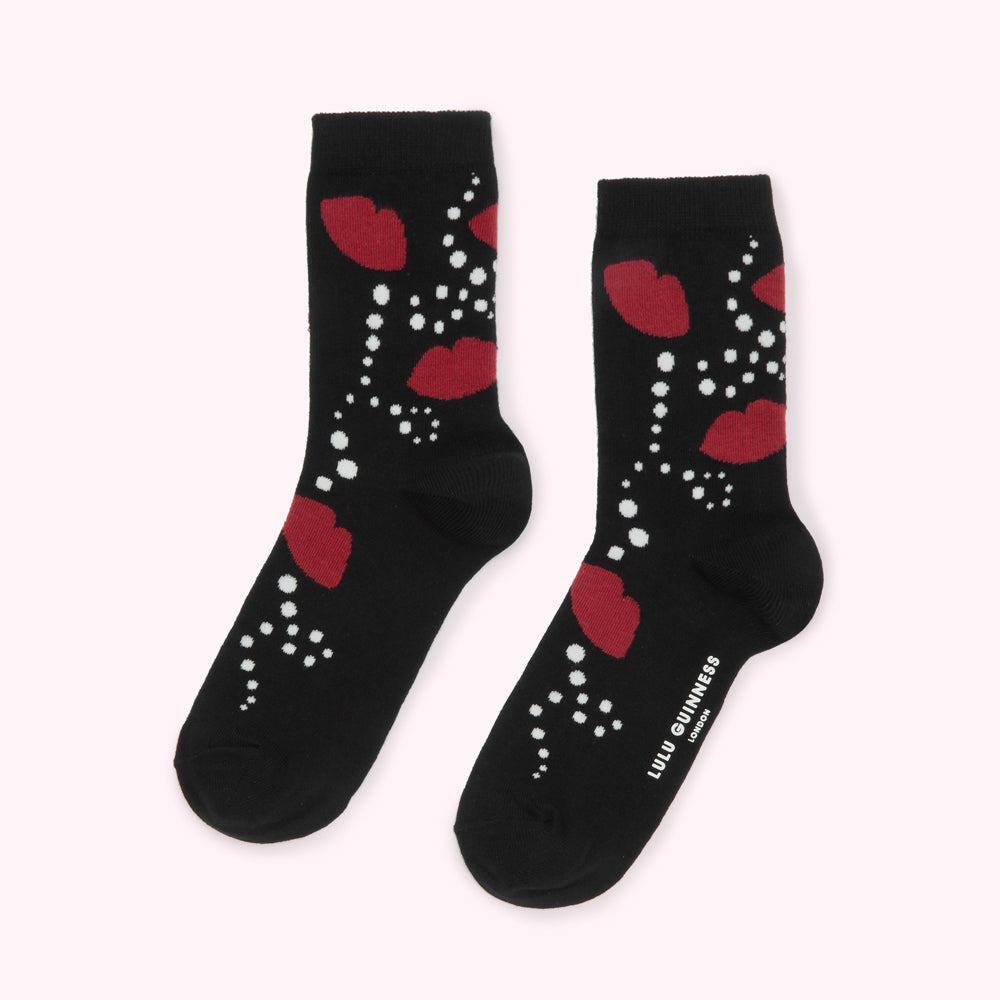 Pair of black socks with a red lips and white dots design. The socks have the Lulu Guinness London logo on one sock.
