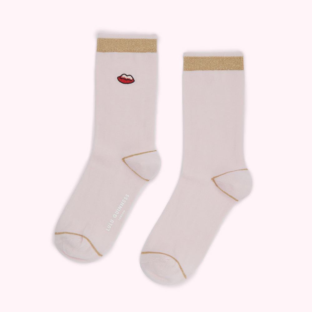 Pair of pale pink socks with gold trim and a small red lip design.
