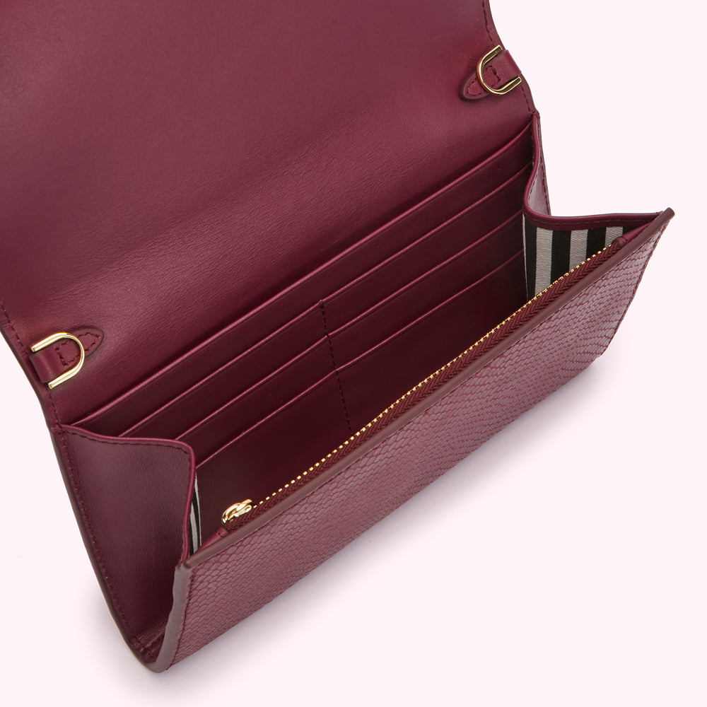 Open burgundy leather wallet with gold hardware and multiple card slots.