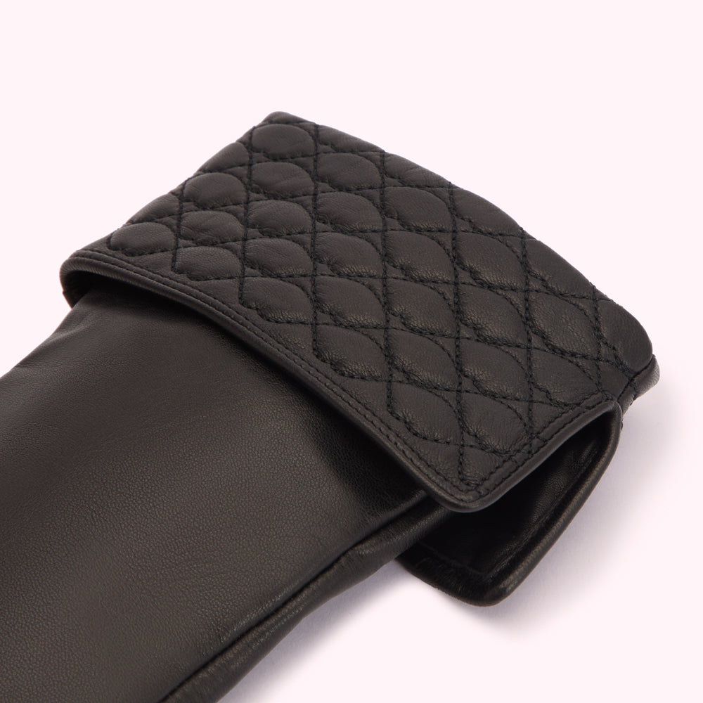 Close-up of black leather gloves with quilted detailing.
