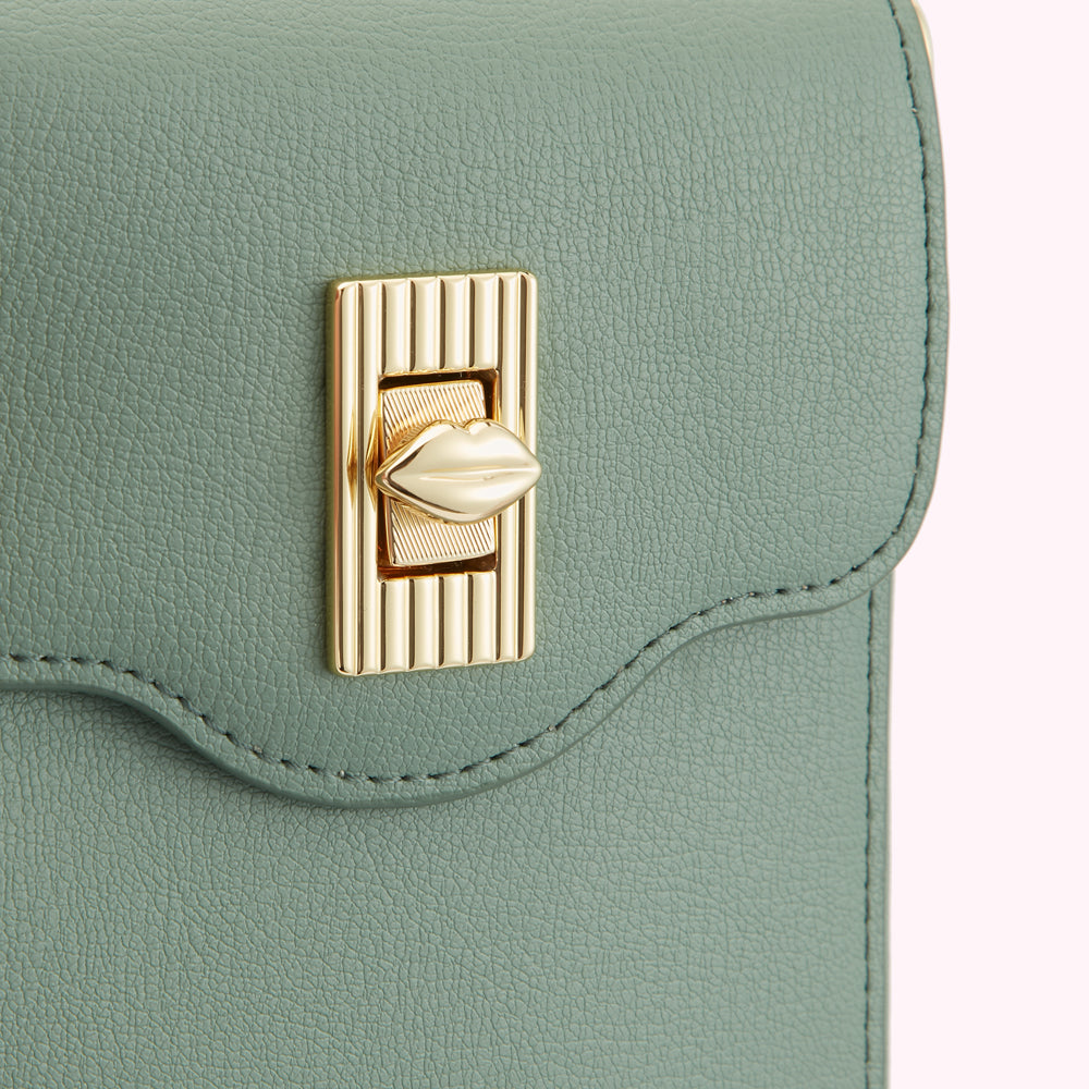 Close-up of a sage green purse with a gold lip-shaped clasp.
