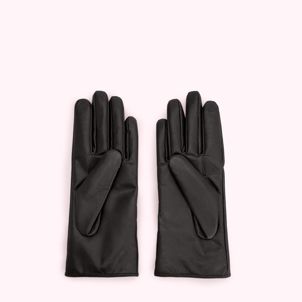 Pair of black leather gloves on a light pink background.
