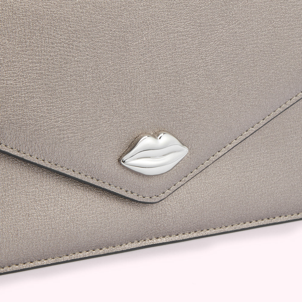 Close-up of a metallic silver envelope-style clutch with a silver lip-shaped detail.
