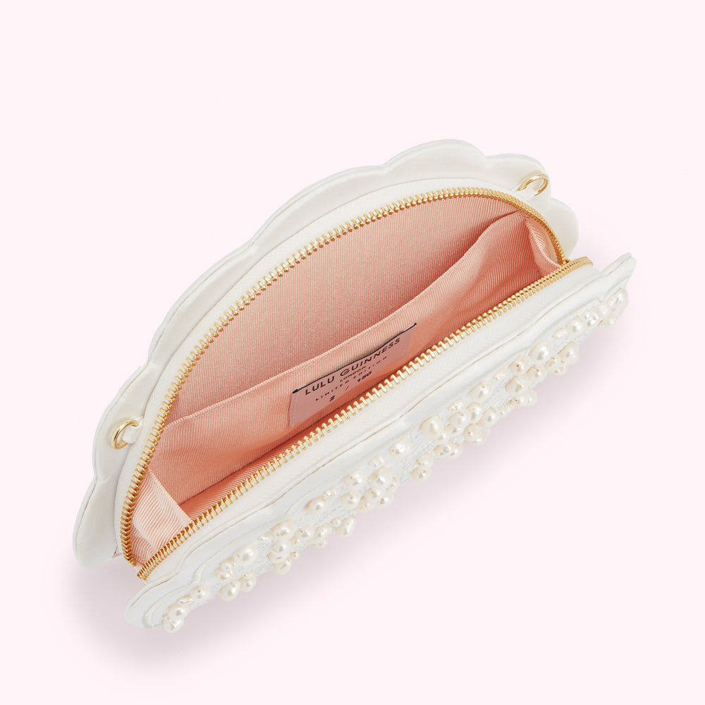 Open white Lulu Guinness fan-shaped clutch embellished with pearls, showcasing a pale pink interior.
