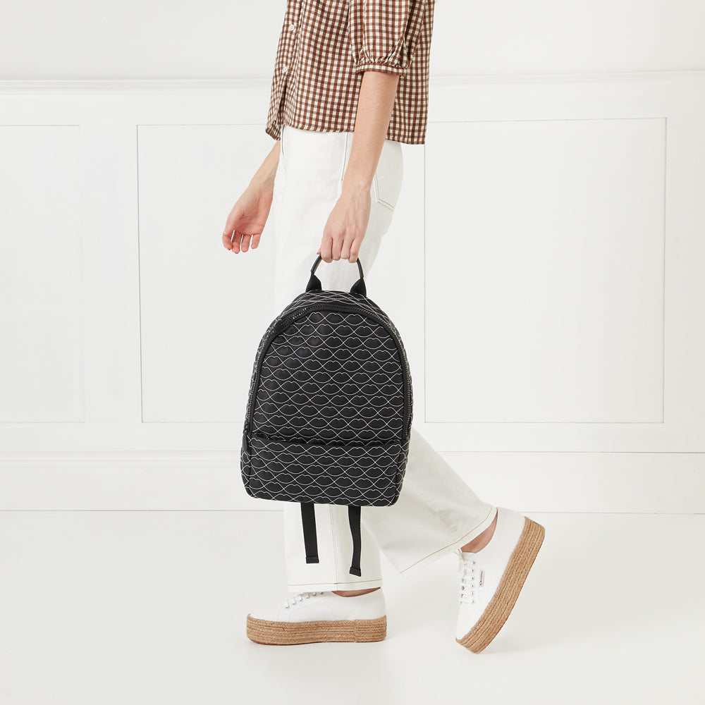 A person carrying a black backpack with a white lip print on a white background.