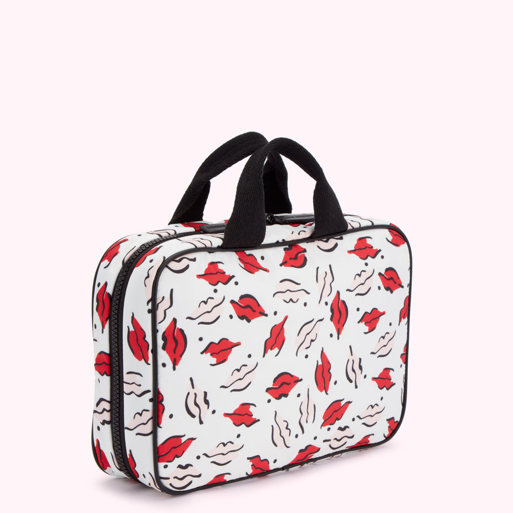 White and black rectangular cosmetic bag with a red lips print and black handles.