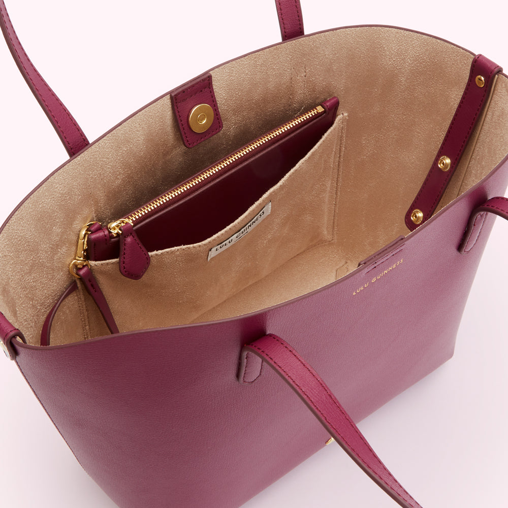 Inside view of a burgundy Lulu Guinness tote bag with a beige interior and a smaller zipped pocket.