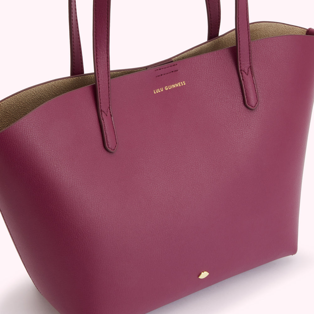Close-up of a dark burgundy Lulu Guinness tote bag with beige interior.
