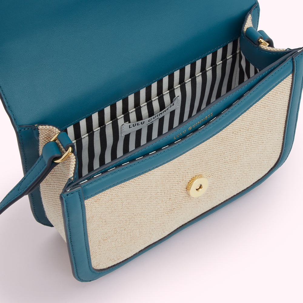Interior of a teal and beige Lulu Guinness crossbody bag.
