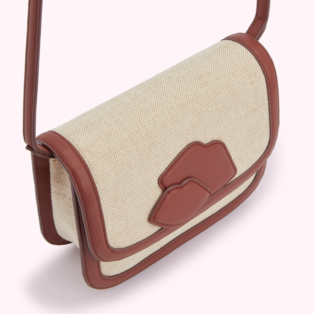 Beige canvas crossbody bag with brown leather trim and lip-shaped detail.
