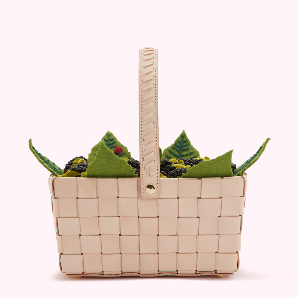 Beige woven leather basket overflowing with embroidered felt blackberries and green leaves.
