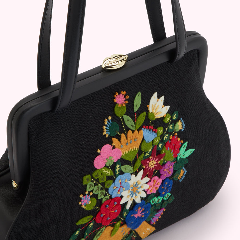 Close-up of a black handbag with embroidered flowers.
