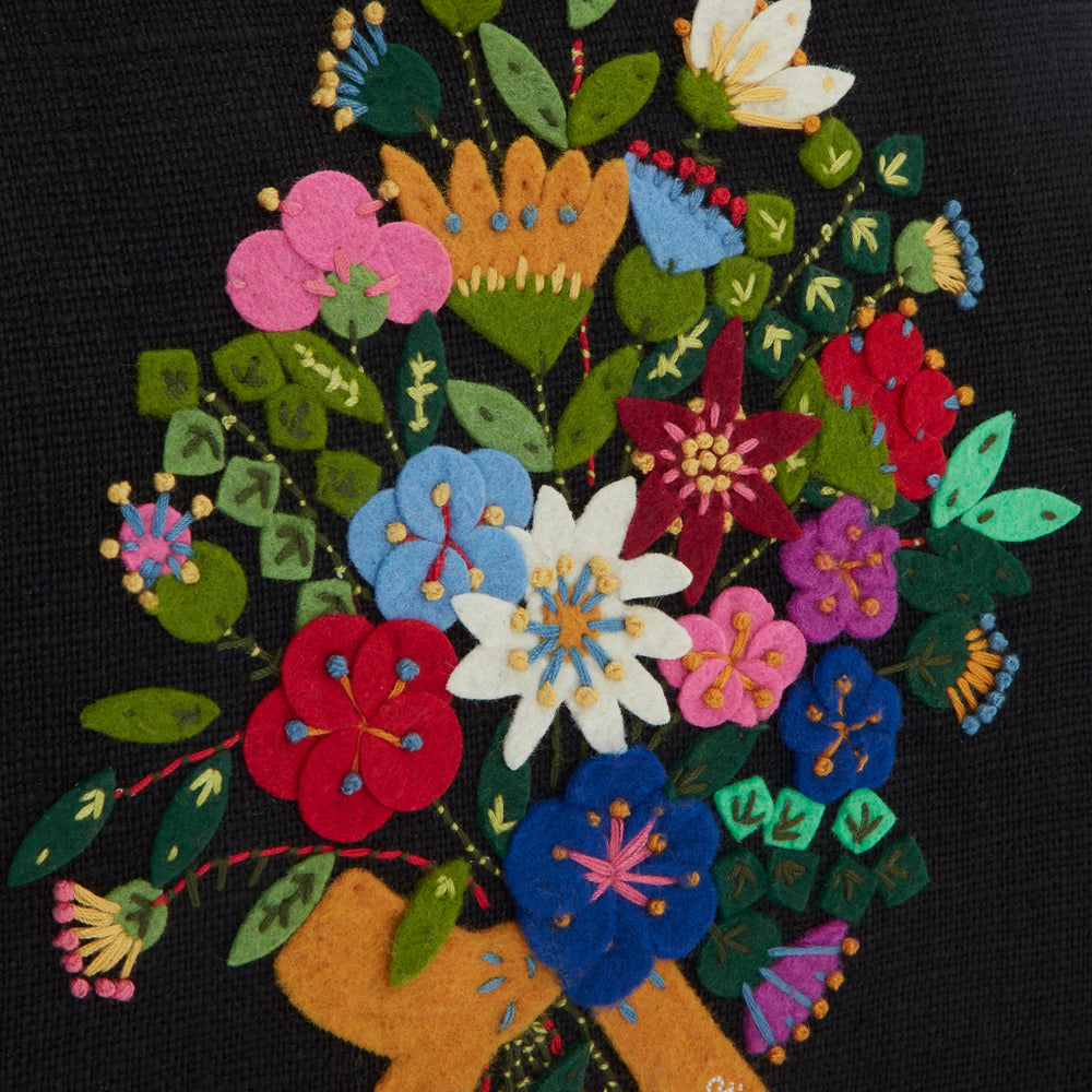 Close-up of a dark-coloured textile featuring an embroidered bouquet of colourful felt flowers.