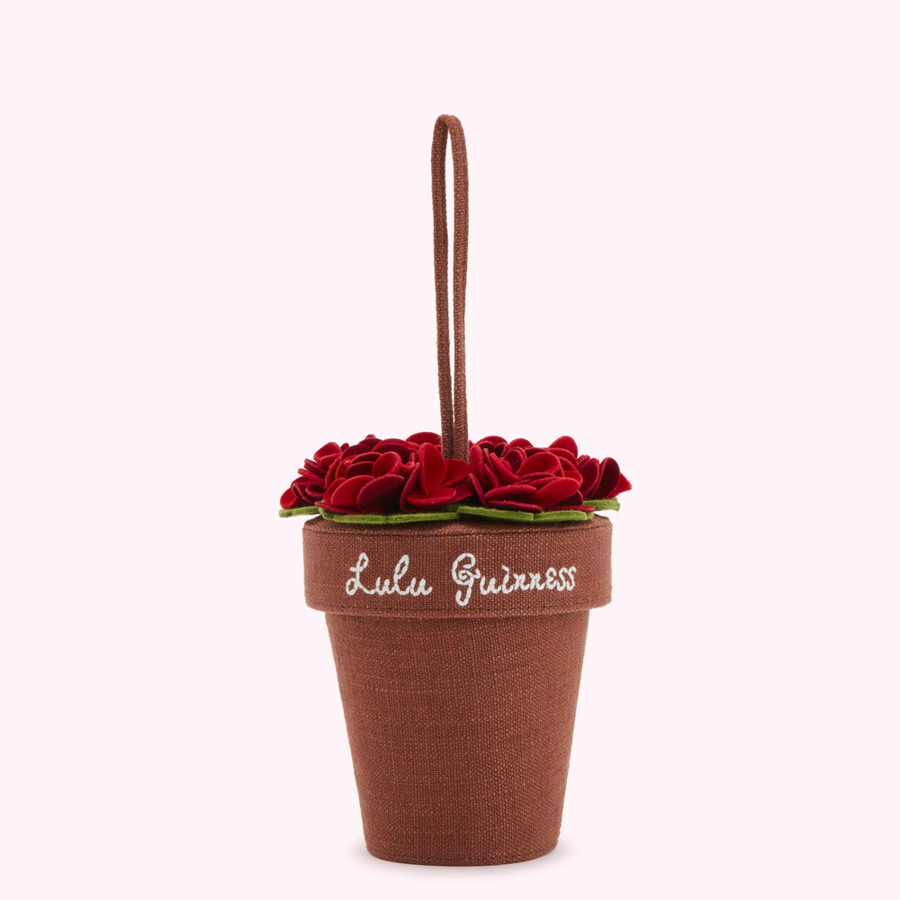 Brown flowerpot-shaped handbag with red felt flowers and "Lulu Guinness" embroidered on the side.