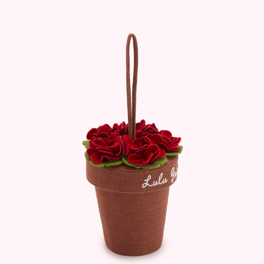 Brown fabric flower pot with red felt flowers and a handle; "Lulu Guinness" embroidered on the side.
