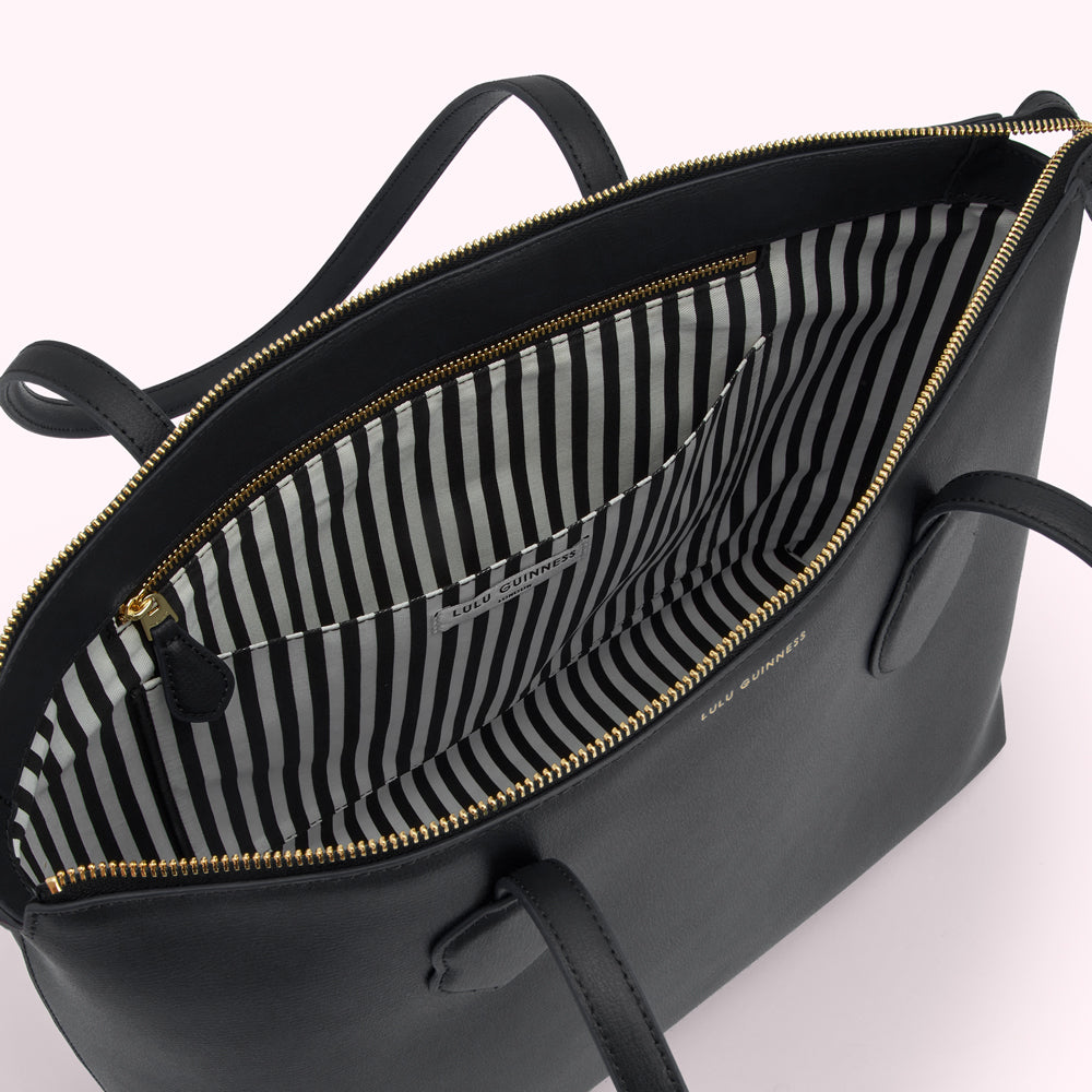 Black Lulu Guinness tote bag open to reveal a black and white striped interior.