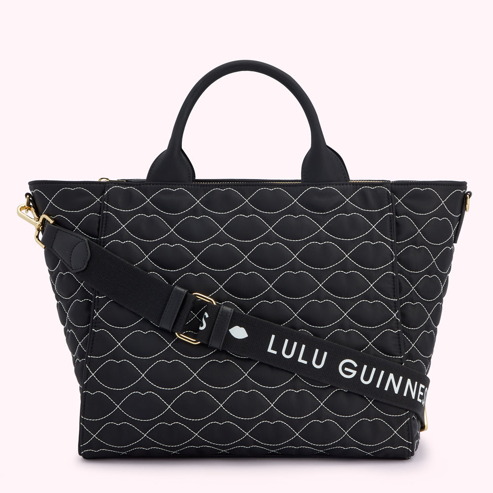 Black quilted tote bag with a white lip pattern and a removable shoulder strap that says "Lulu Guinness".