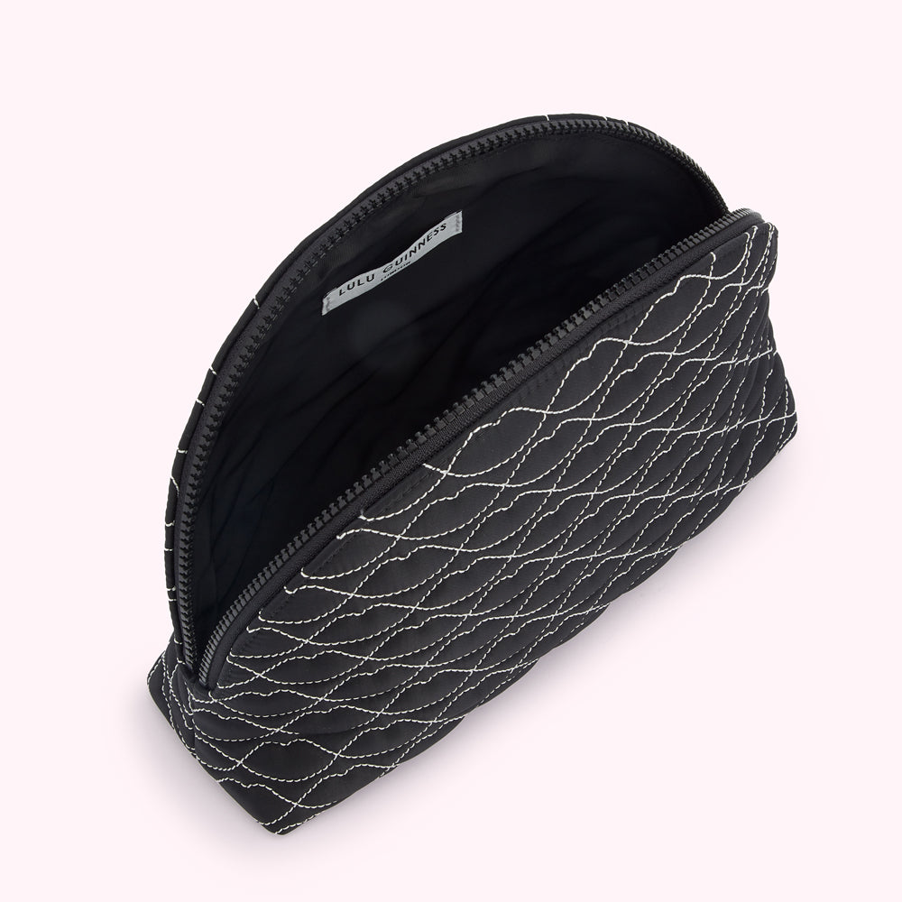Black quilted makeup bag by Lulu Guinness, open to reveal the interior.