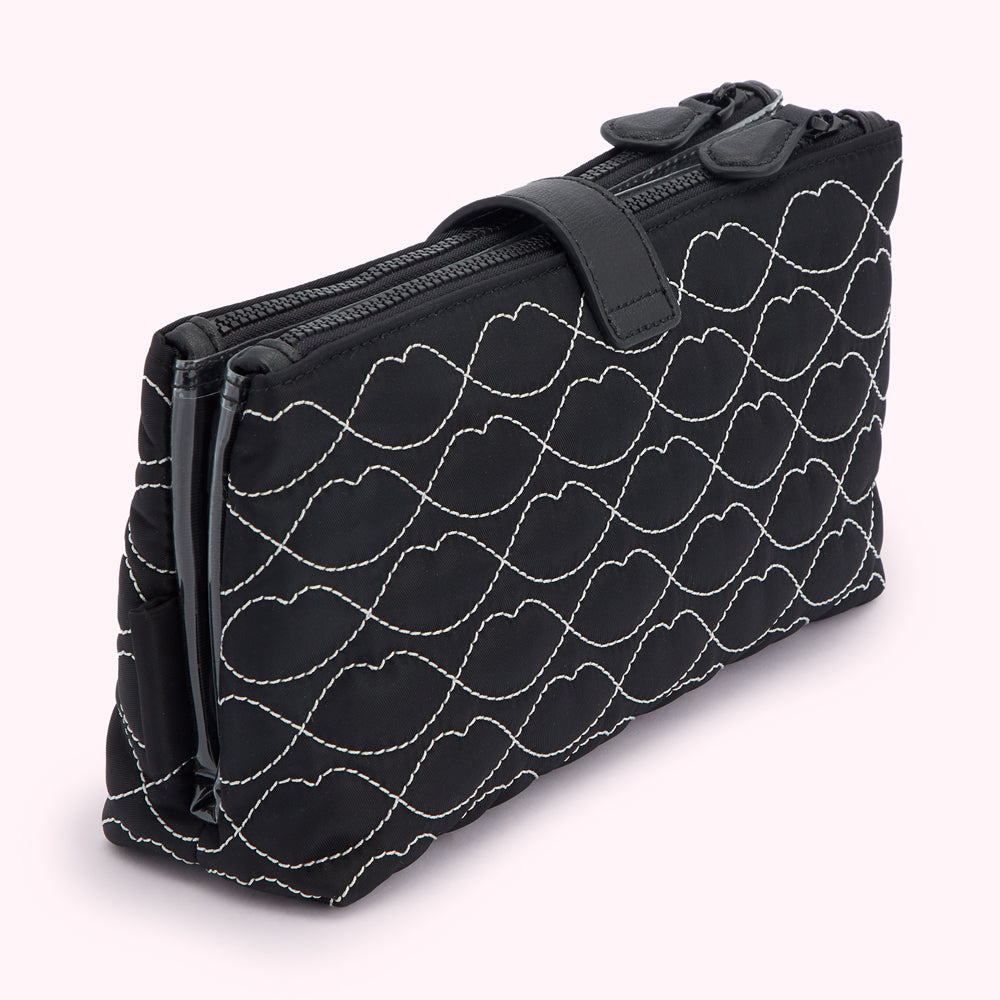 Black quilted makeup bag with white lip print and two zippers.
