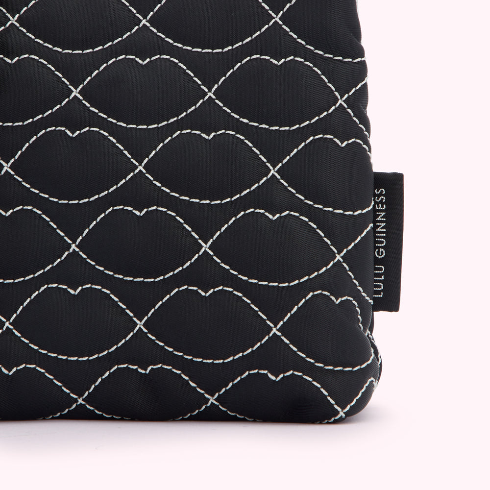 Close-up of a black Lulu Guinness quilted makeup bag with a lip print.
