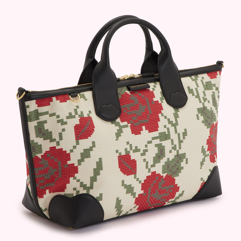 Off-white handbag with a black leather trim and a red and green embroidered rose pattern.