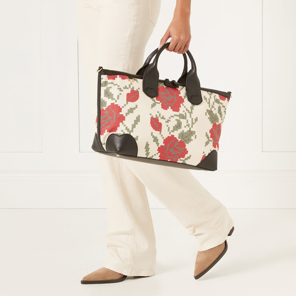 Woman carrying a cream and black floral handbag.
