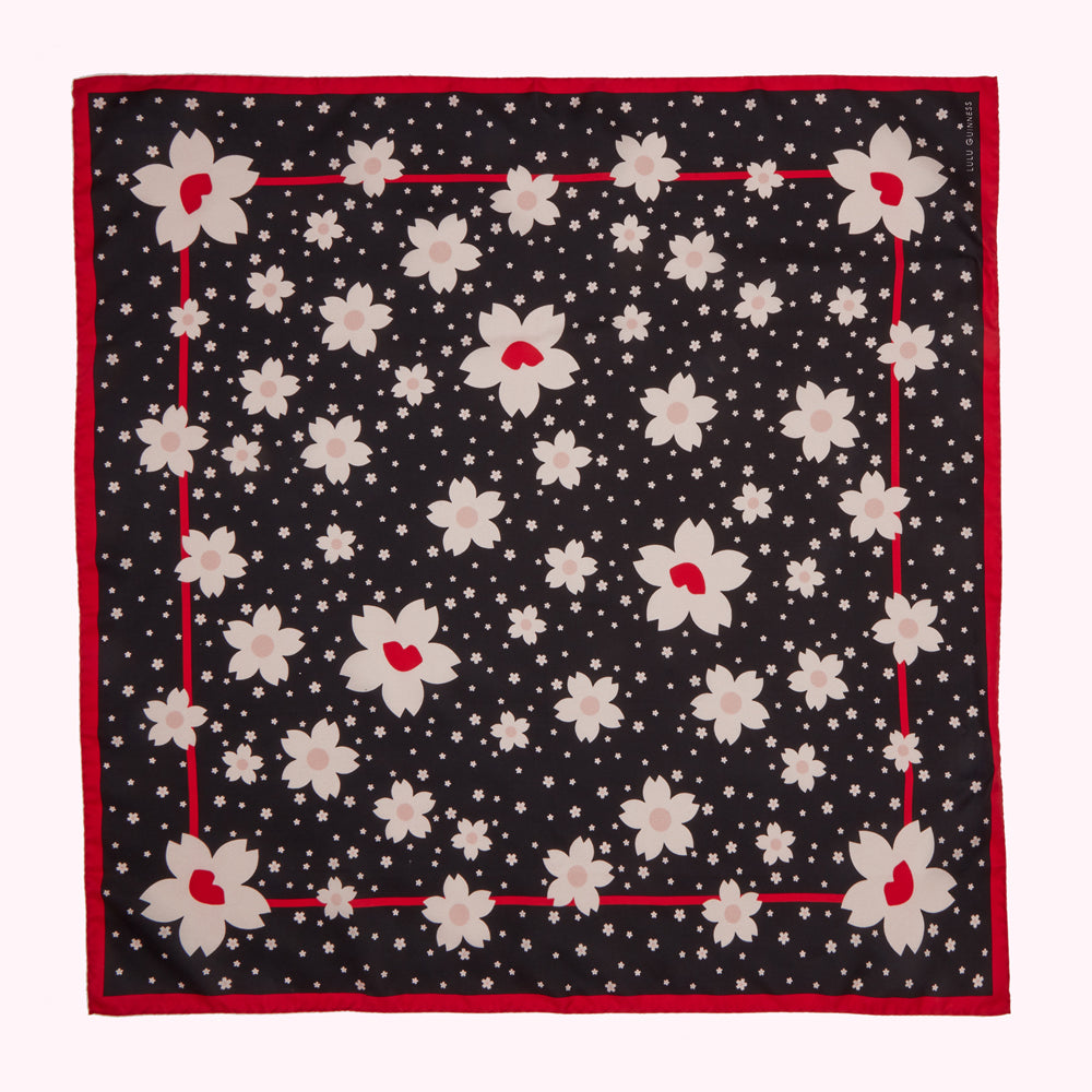 Black silk scarf with a red border and a pattern of stylized cherry blossoms.