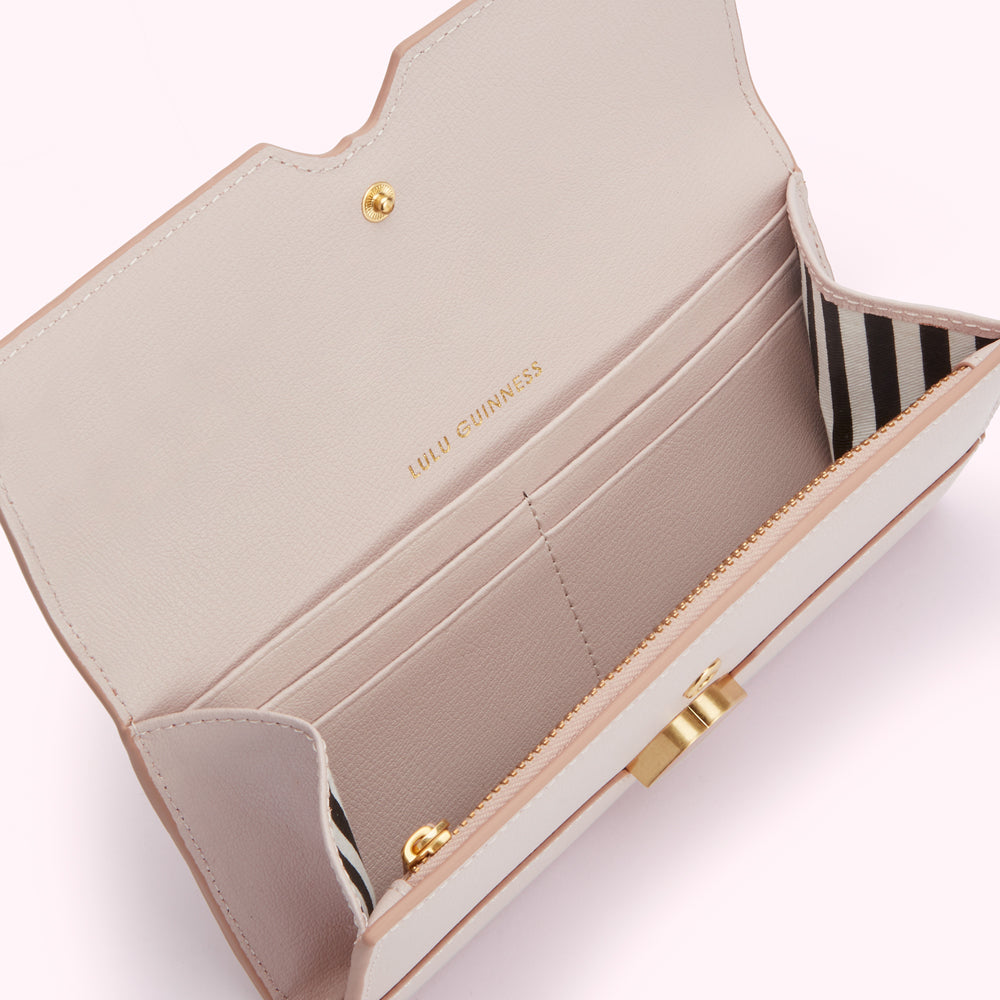 Open blush pink Lulu Guinness wallet with gold zipper and hardware. The interior features multiple card slots and a black and white striped fabric detail.
