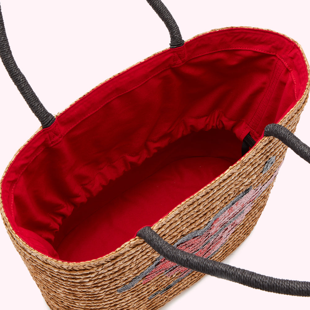 Inside of a straw tote bag with a red lining and lip design.