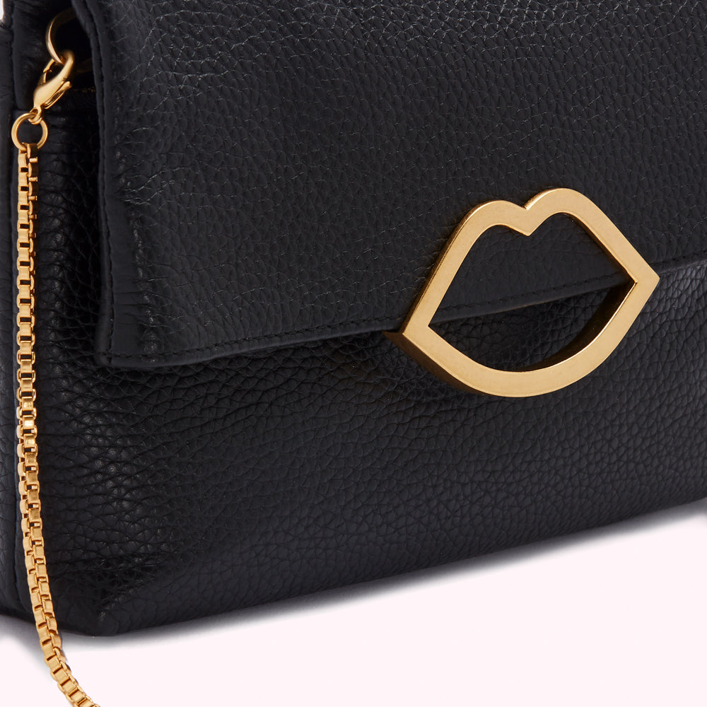 Close-up of a black leather handbag with a gold lip-shaped clasp and a gold chain strap.
