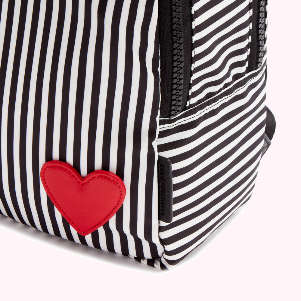 Close-up of a black and white striped backpack with a red heart detail.