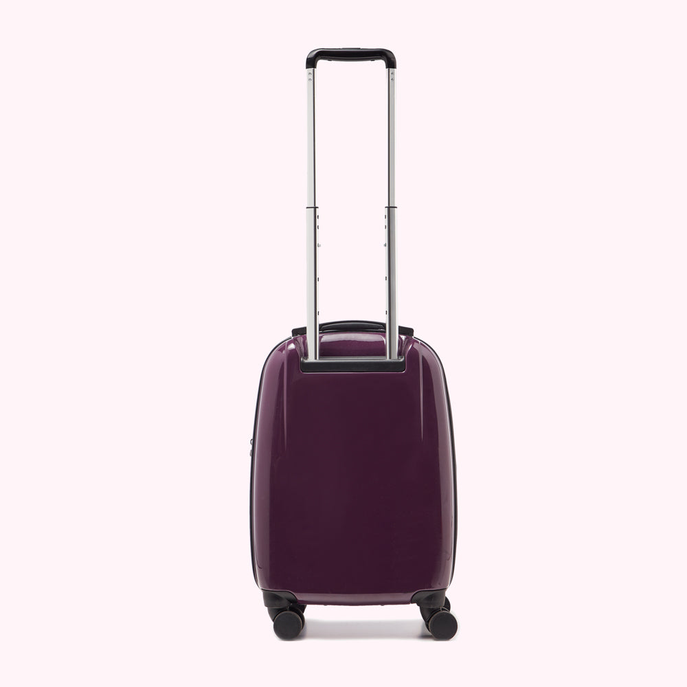 Rear view of a dark purple carry-on suitcase with a silver handle.
