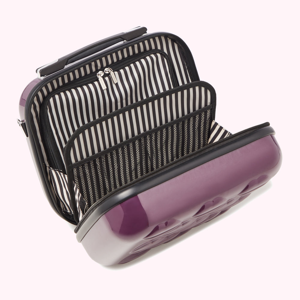 Purple hard-shell carry-on makeup case open to reveal its black and white striped interior compartments and mesh pocket.
