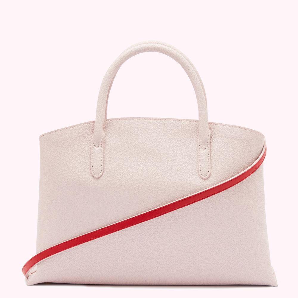 Light pink leather handbag with a red shoulder strap.
