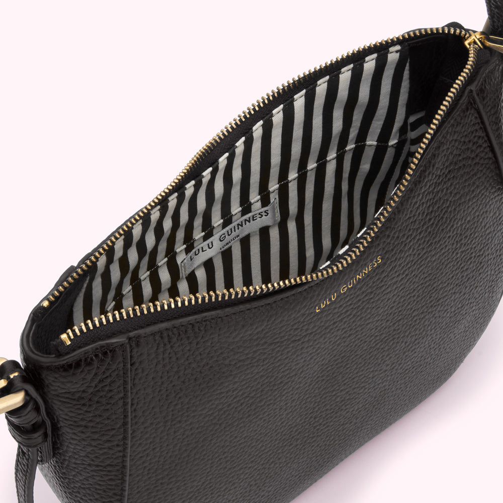 Open black Lulu Guinness crossbody bag with black and white striped interior.