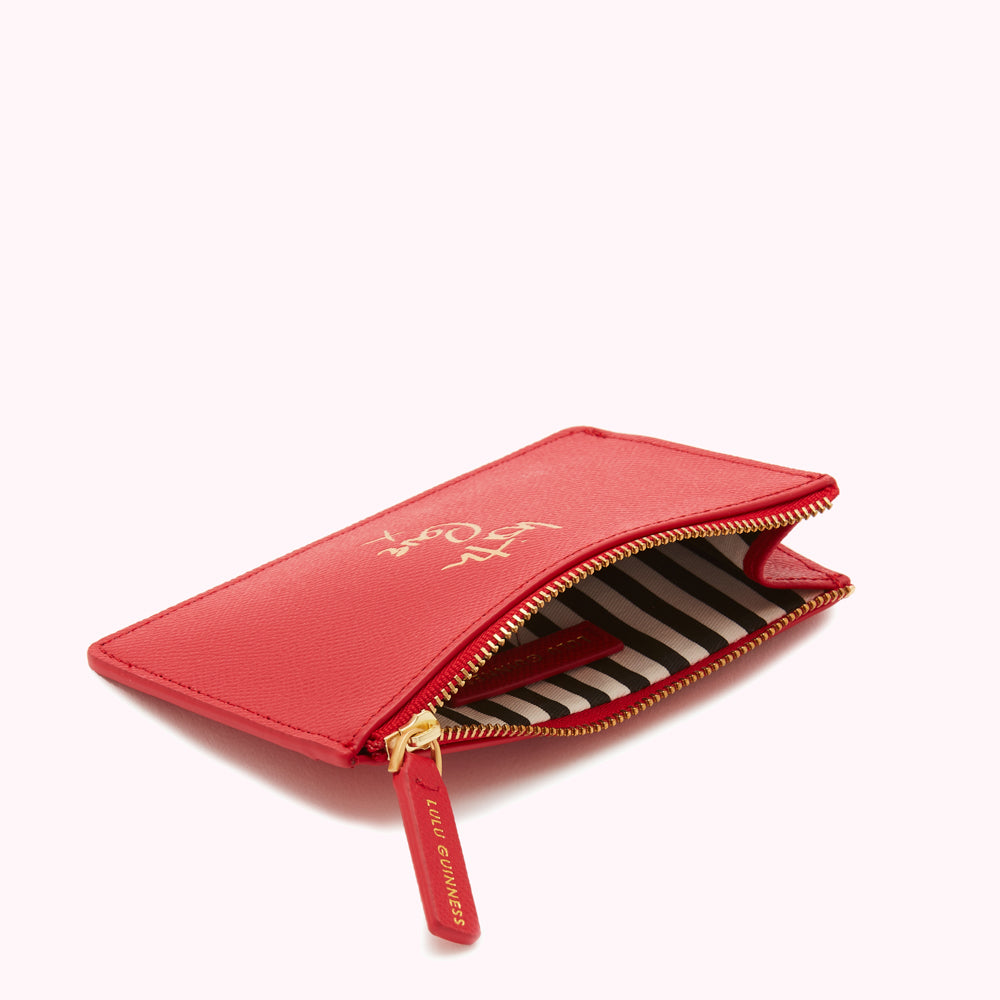 Red leather zip pouch with gold lettering and black and white striped lining.