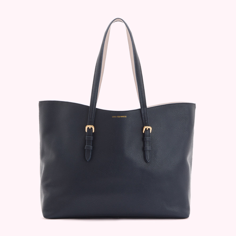 Navy blue Lulu Guinness tote bag with beige handles and gold buckles against a white background.
