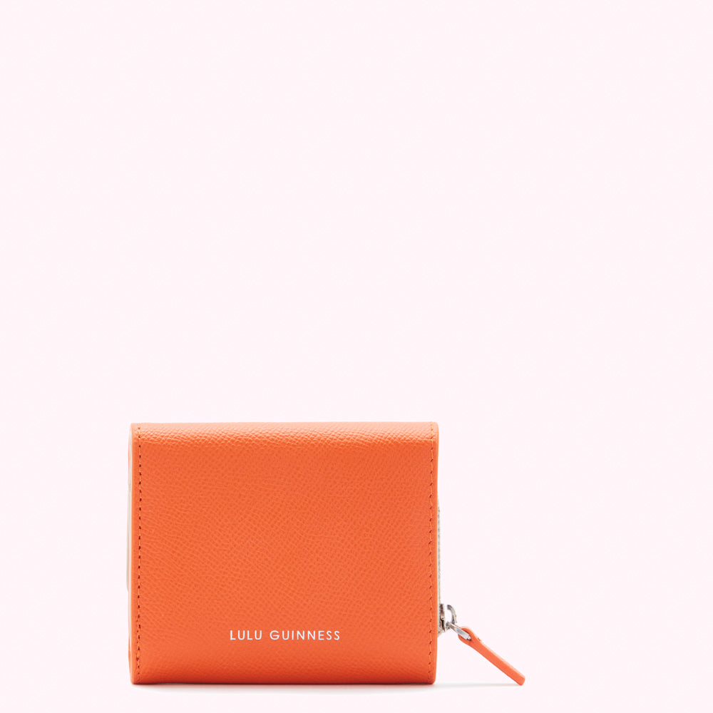Orange Lulu Guinness wallet on white background.