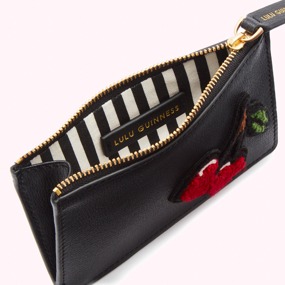 Black Lulu Guinness cardholder with red cherry embroidery and black and white striped interior.
