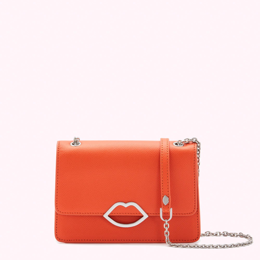Orange leather crossbody bag with silver lip-shaped clasp and chain strap against a white background.
