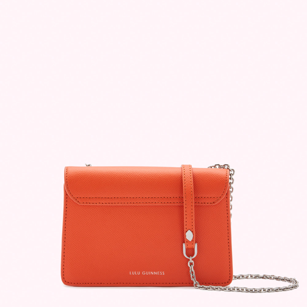 Orange Lulu Guinness crossbody bag with silver chain strap.
