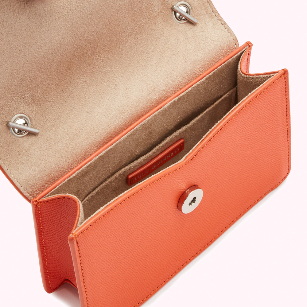 Orange Lulu Guinness mini crossbody bag open to reveal beige interior.